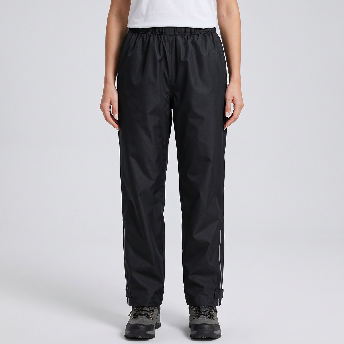 Women's rain trousers in Black, front view, elasticated waist, reflective strips and ankle tabs