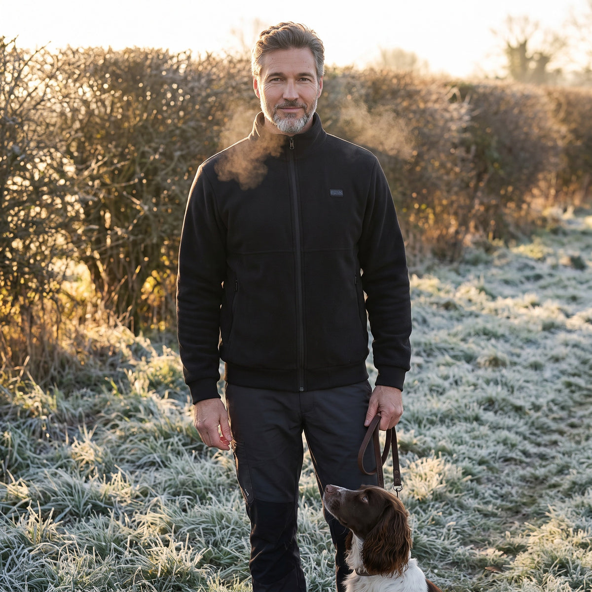 Man wearing the heated jacket in Black on an early frosty dog walk with his spaniel