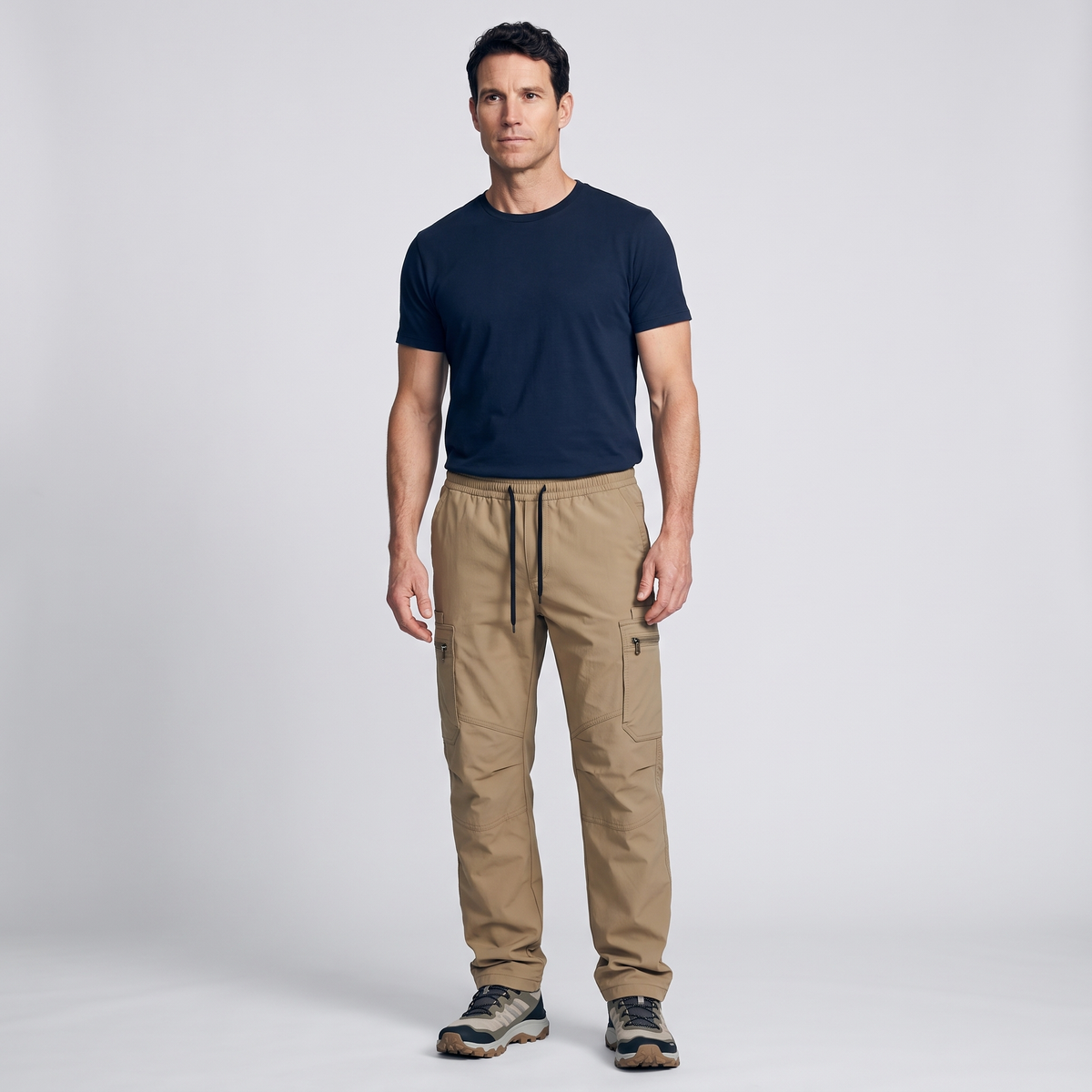 Man wearing Dark Khaki combat trousers, full length, with a navy t-shirt and trail shoes