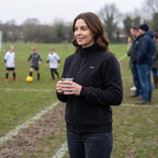 Woman wearing the heated fleece jacket on the touchline of a junior football match