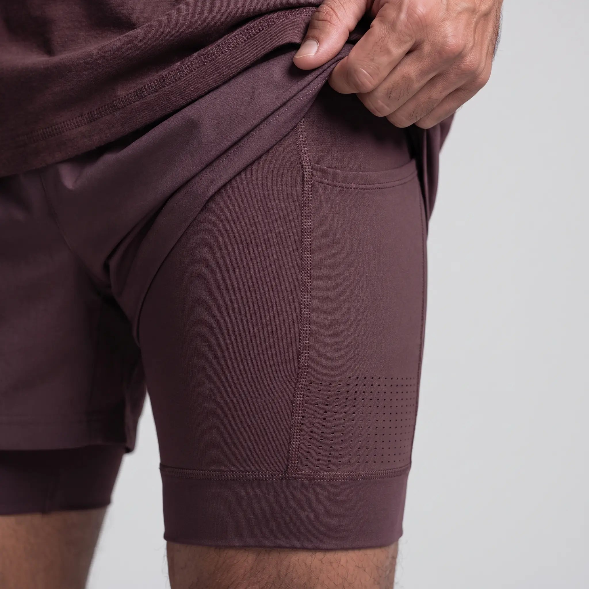 Close-up of the compression liner showing the bonded seam, laser-cut ventilation perforations and thigh phone pocket