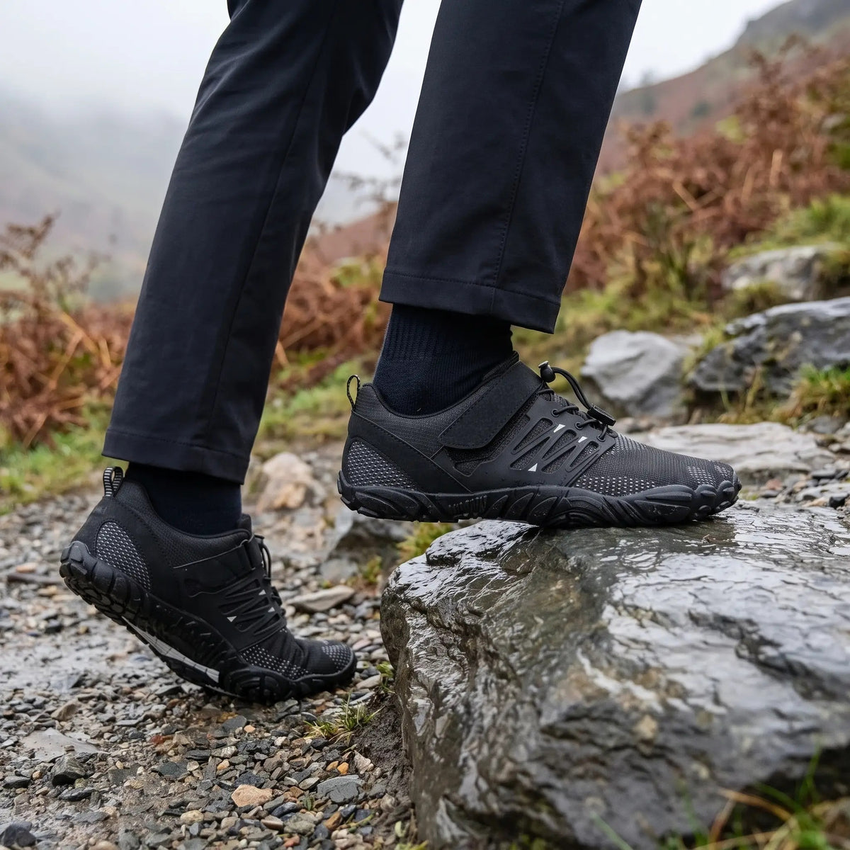 Black barefoot shoes stepping onto wet rock on a fell path