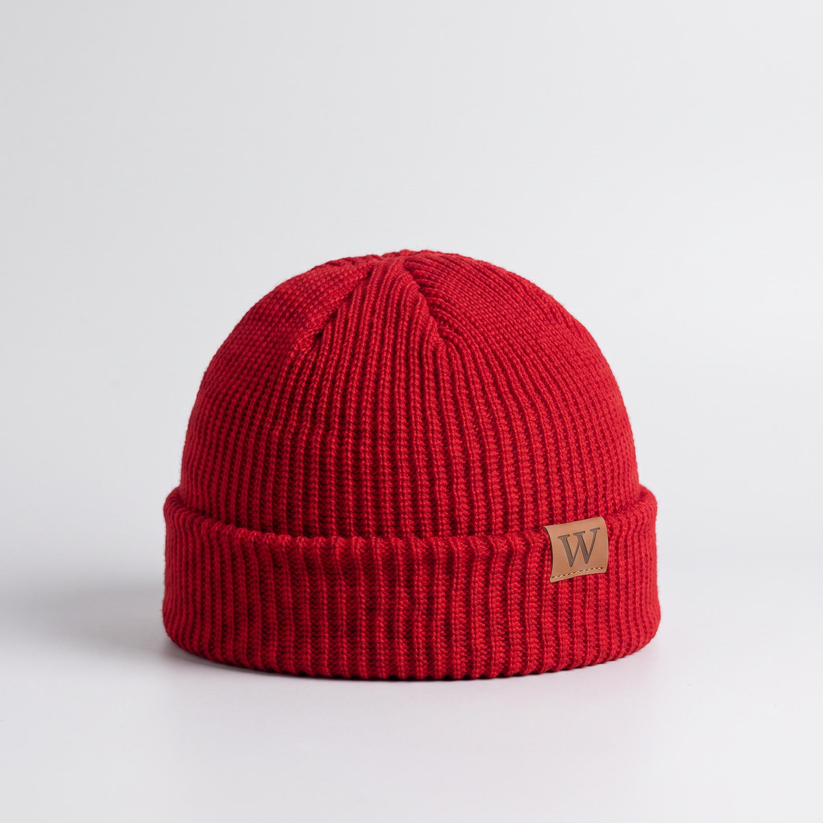 Red ribbed fisherman beanie with a turned cuff and leather label