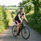 Woman riding a road bike on a hedge-lined country lane in Britain wearing the Women's Cycling Shorts