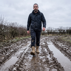 Man walking across a rutted muddy field in Britain wearing the boots