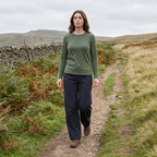 A woman walking a British upland path in the women's wide leg walking trousers, dry stone wall and bracken beside the track