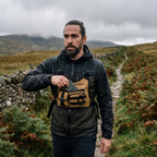 Man taking his phone from the chest bag without stopping on a fell path