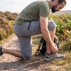 Walker kneeling on a moorland path in 3/4 cargo shorts, knee covered