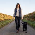 Woman walking a black labrador along an English country lane wearing the Navy quilted gilet