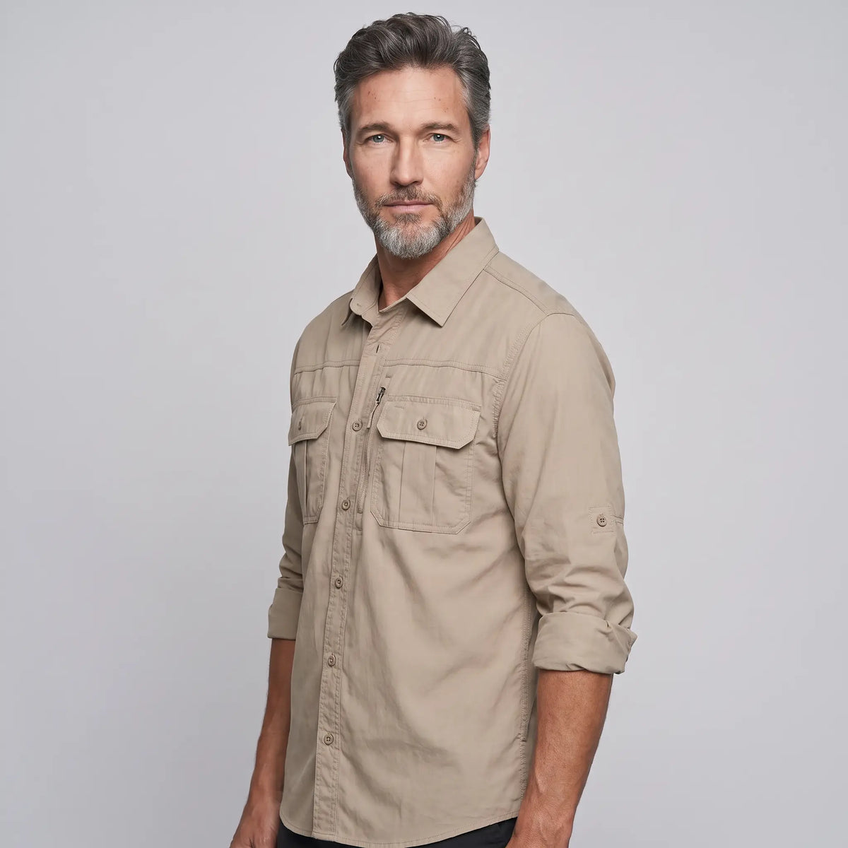 Man wearing the men's fishing shirt in Khaki with the sleeves rolled up and buttoned on their tabs