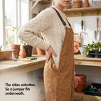 Buttoned side opening of the dungarees worn open over a cable-knit jumper