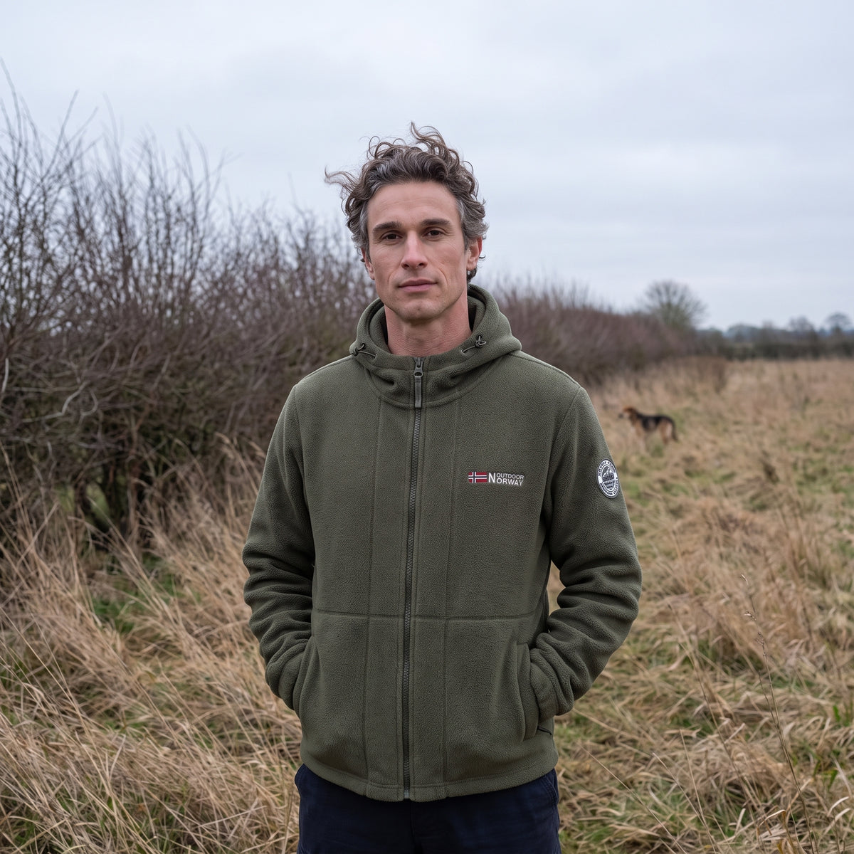 Man standing in a winter field in the army green windproof fleece jacket