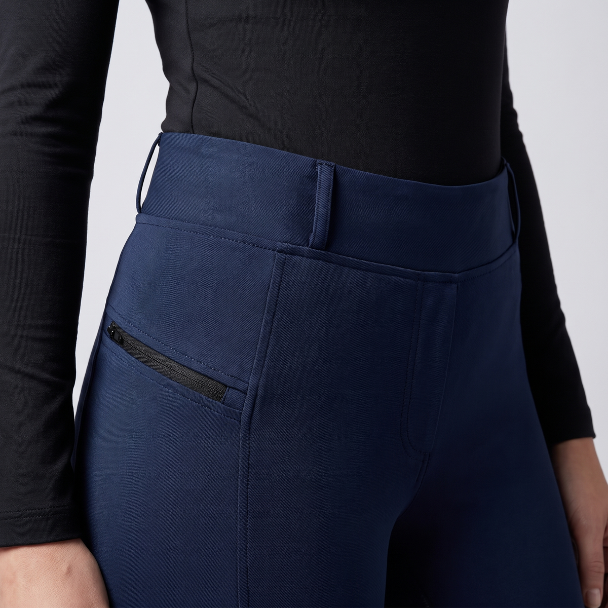 Close-up of the wide high waistband, belt loops and zip pocket on navy jodhpurs