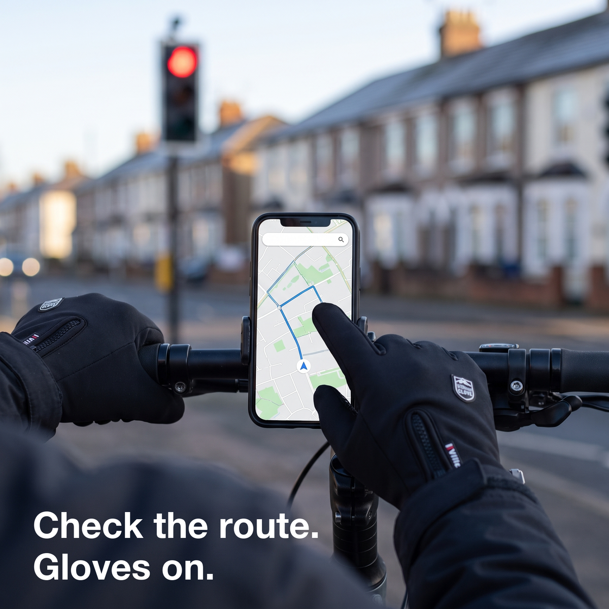 Gloved finger checking the route on a handlebar phone at a red light, gloves on