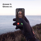 Gloved thumb answering a phone call on a cliff-top coast path