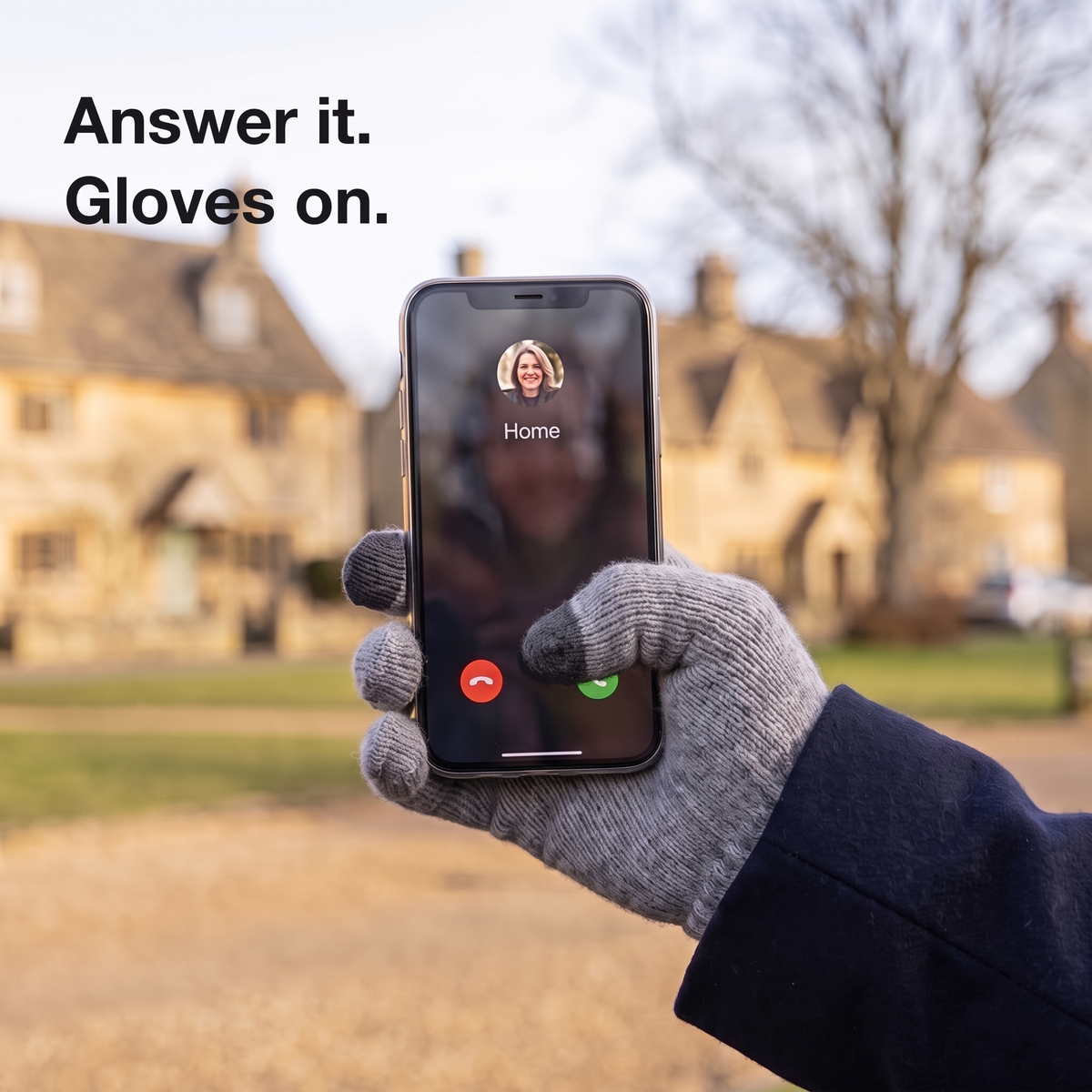 Gloved thumb answering a phone call on a Cotswold village green
