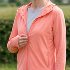Close-up of a hand drawing the full-length front zip down, grey t-shirt visible underneath