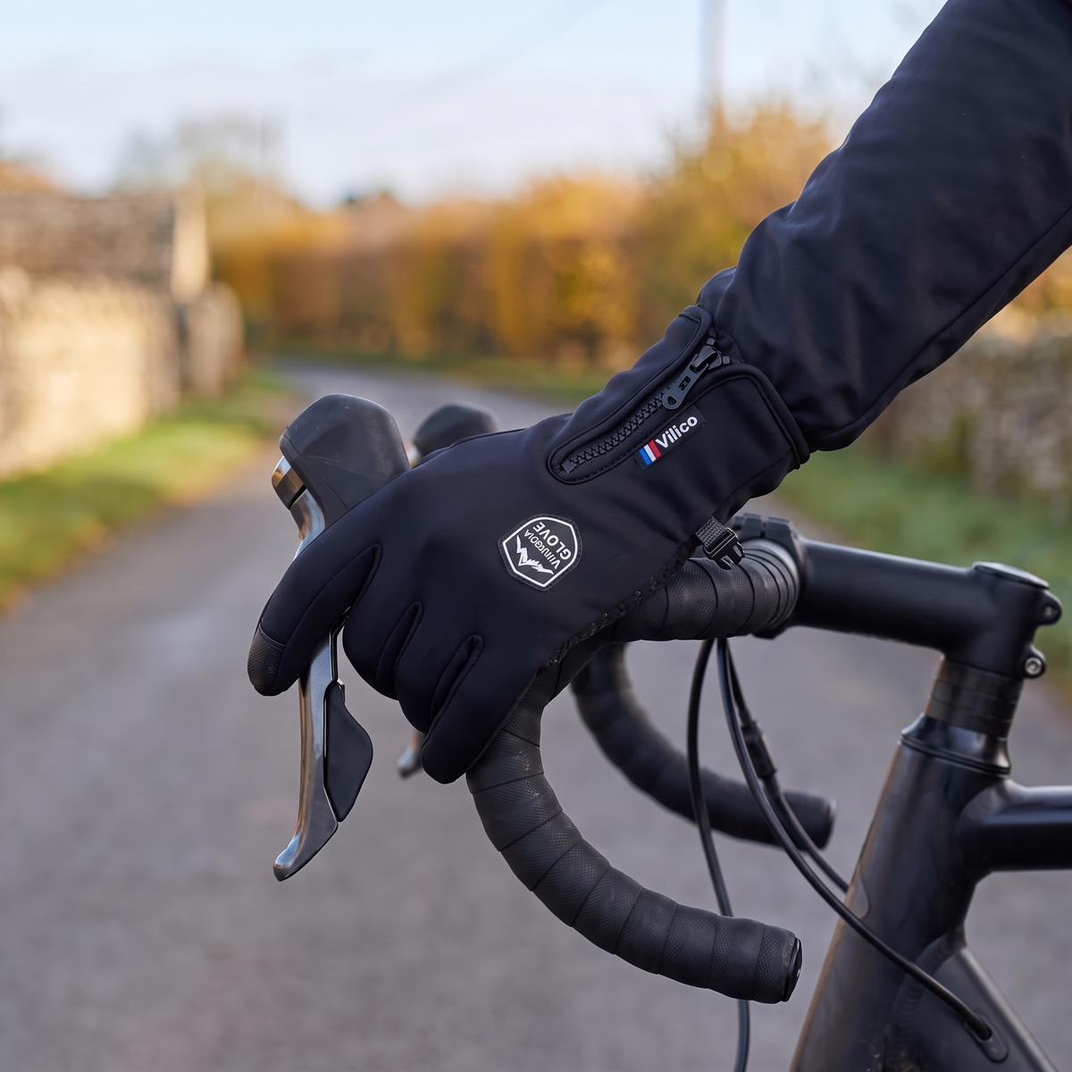 Gloved hand on a road bike brake hood with two fingers on the lever