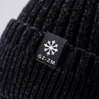 Close-up of the double-layer turn-up cuff and woven snowflake label on the black winter hat