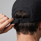 Hand tightening the clip buckle strap at the back of the running cap