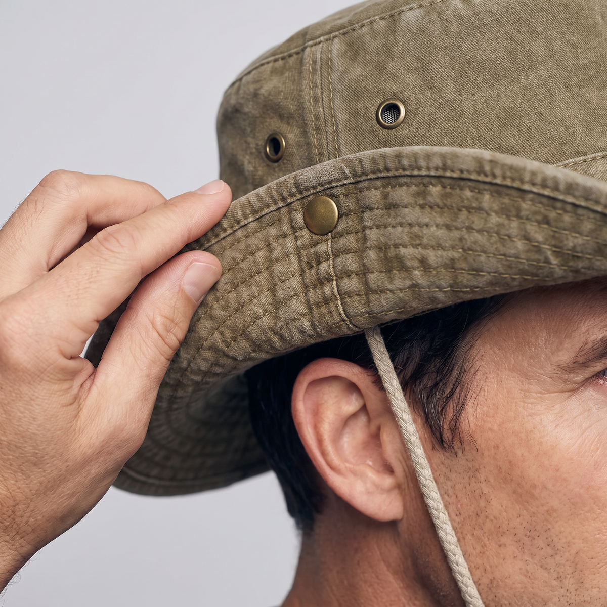 Fingers pressing the side snap to pin the brim of the sun hat up to the crown