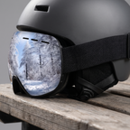 Ski goggles fitted over a helmet with the wide adjustable strap