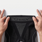 Hands stretching the wide knitted ESDY logo waistband of the black base layer leggings