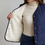 Front of the gilet held open to show the soft cream fleece lining and metal poppers