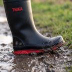 Lugged red sole of the mid-calf welly biting into a muddy path