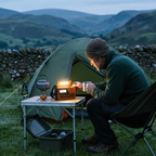 Man listening to the portable radio by its reading light at a campsite at dusk