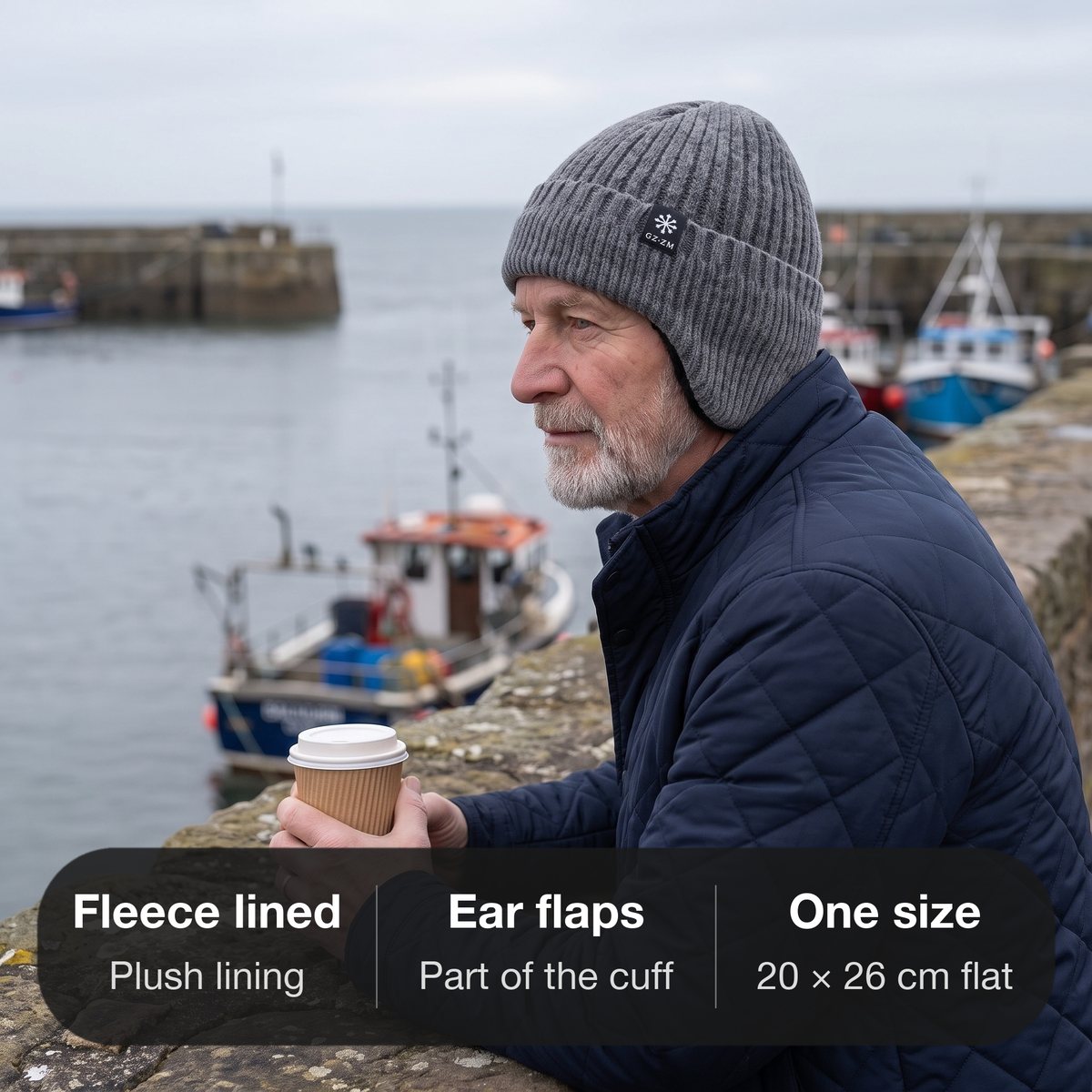 Man in the grey knitted winter hat on a harbour wall on the British coast