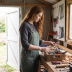 Woman sorting tools at a workbench in green canvas bib dungarees