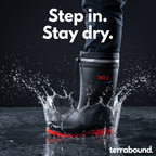 Welly stamping into a puddle, the splash frozen around the shaft below the closed cuff