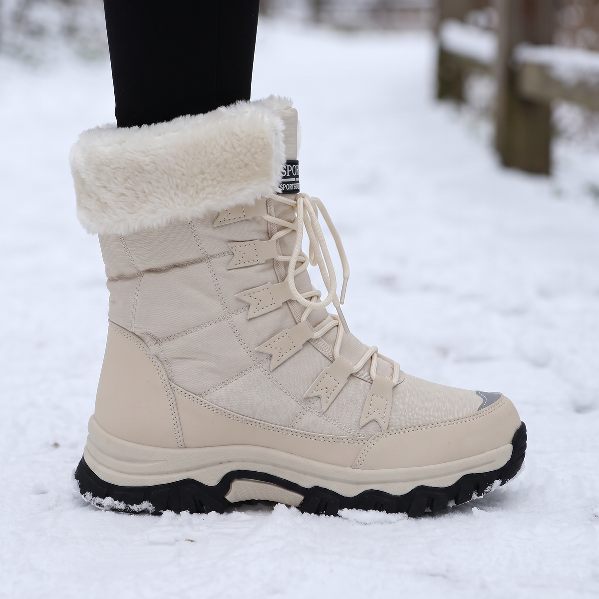 Lugged rubber outsole of the snow boot pressed into packed snow