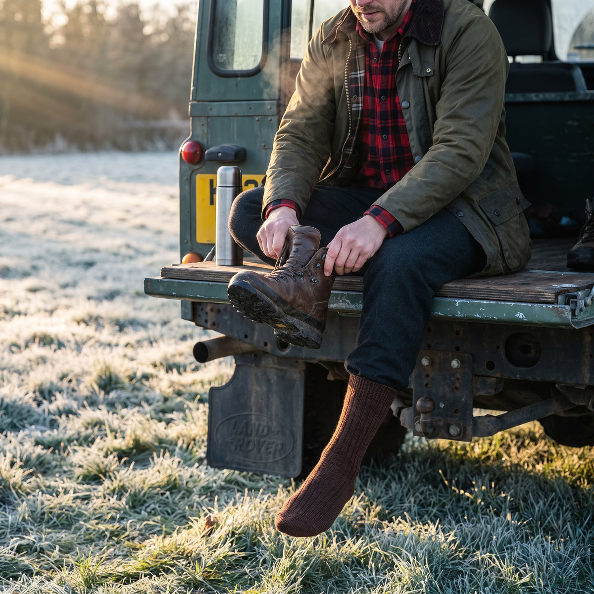 Man pulling on walking boots over brown wool socks on a frosty morning