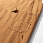 Snap-closed bib chest pocket on the camel canvas dungarees