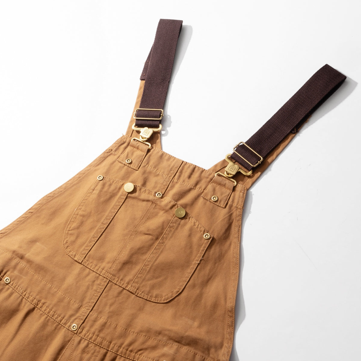 Camel canvas bib dungarees laid flat showing the bib, straps and side buttons