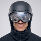Man wearing the black ski goggles over a ski helmet, studio front view