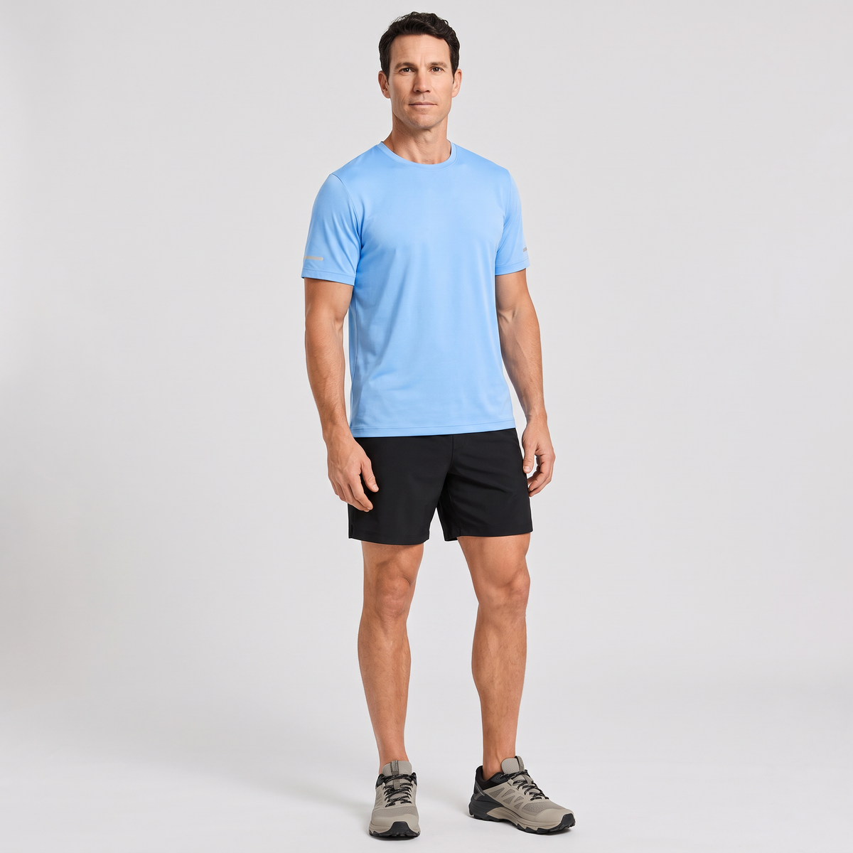 Man wearing the men's running top in Sky Blue with black running shorts, full length
