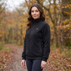 Heated fleece jacket worn by a woman, three-quarter view on a woodland path