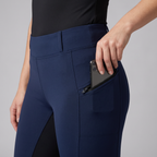 Phone sliding into the zip pocket on the hip of navy riding jodhpurs