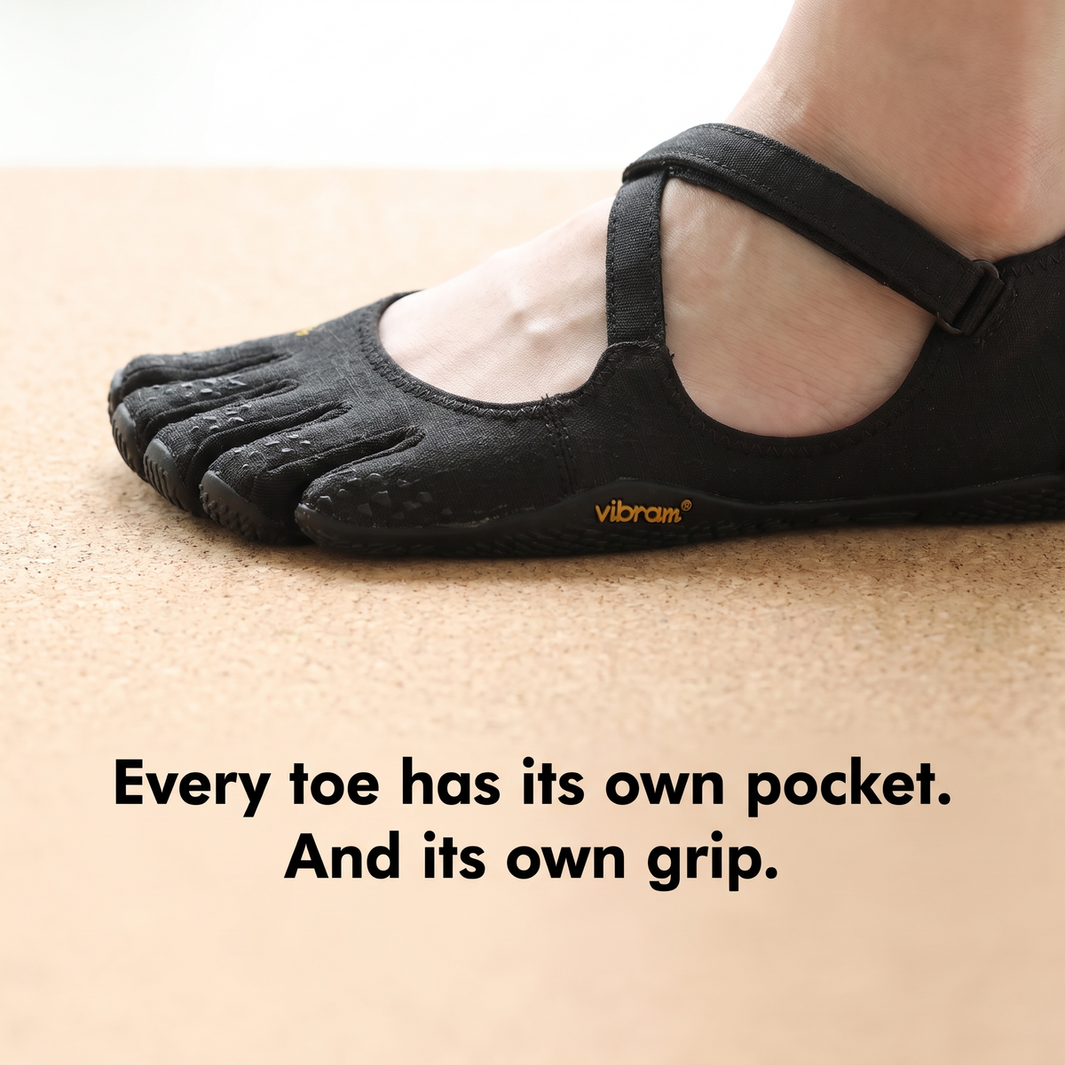 Close-up of a black five toe shoe on a cork yoga mat, each toe pocket gripping on its own