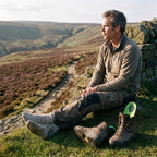 Walker resting on a drystone wall after a hill day, an arch support insole pulled out of his walking boot