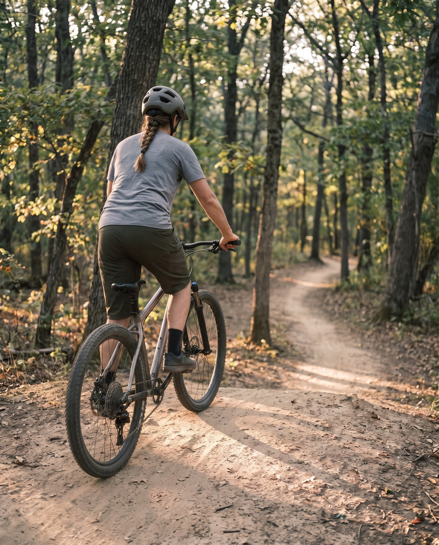 Woman mountain biking in baggy shorts on a woodland trail