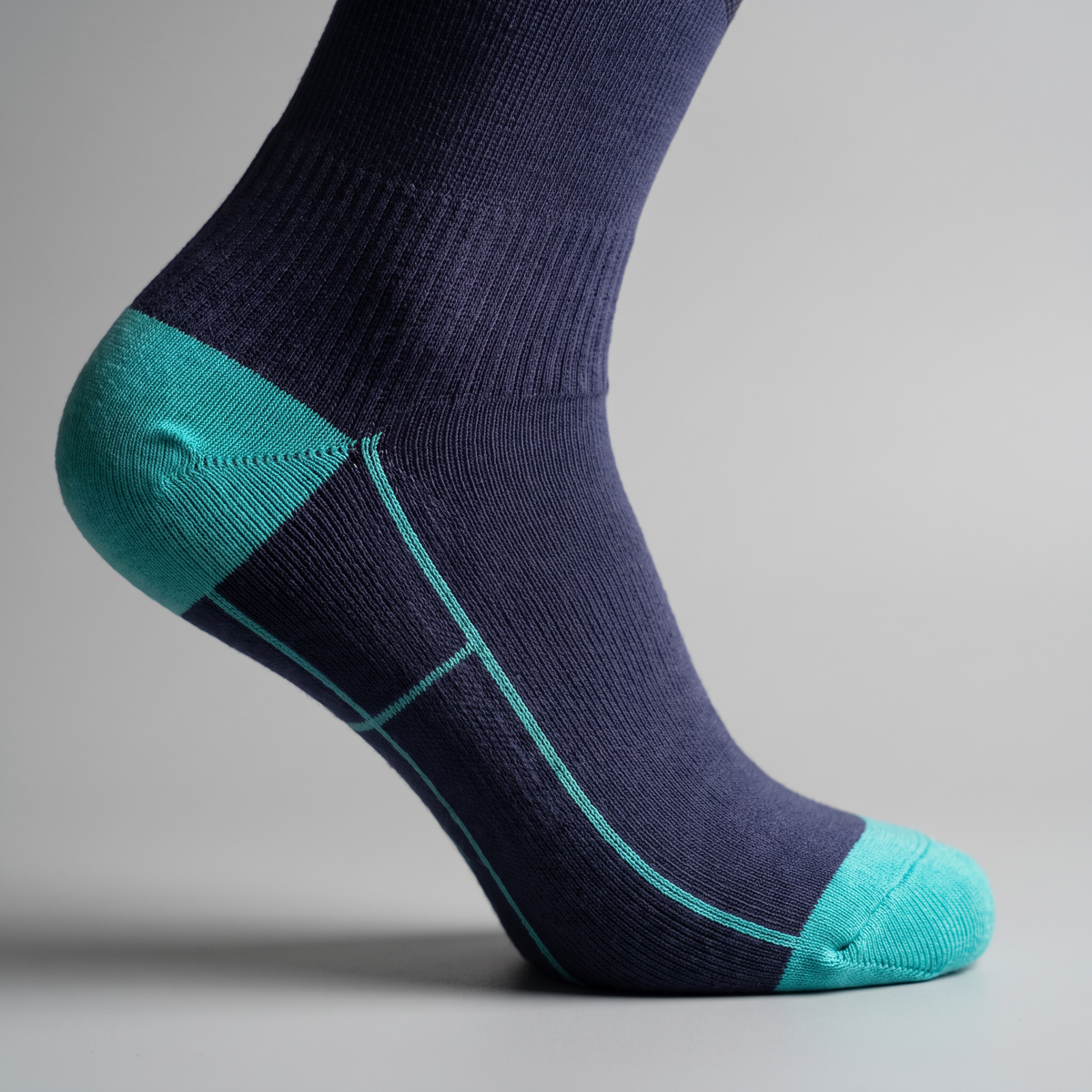 Close up of the reinforced heel and toe with teal contrast panel on the navy sock