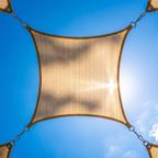 Looking up at a beige shade sail pulled taut against a blue summer sky