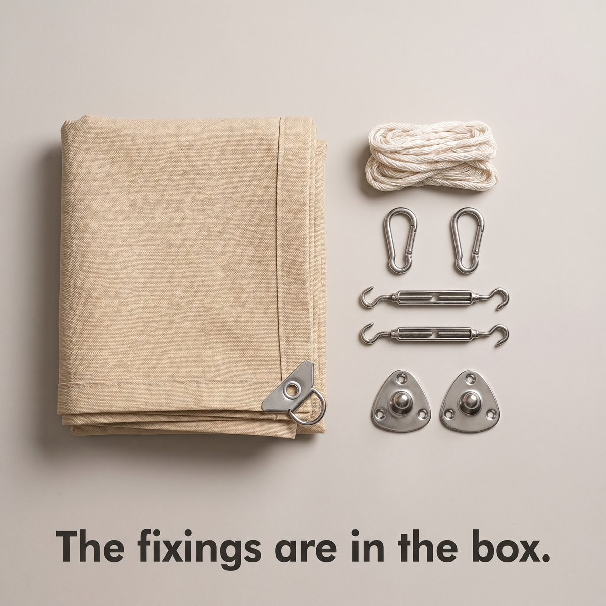 Folded beige shade sail with its fixings laid out: rope, carabiners, turnbuckles and wall plates
