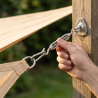 Hand tightening a turnbuckle between the shade sail corner D-ring and a wall plate on a timber post