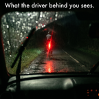 Driver's view through a rainy windscreen of a cyclist's bright red rear light
