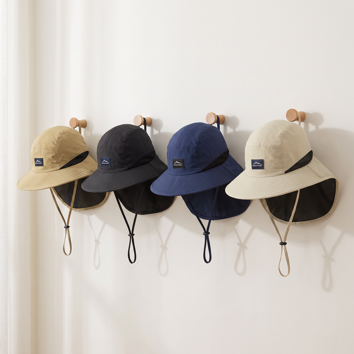 The sun hat with neck flap in Khaki Tan, Black, Blue and Sand Beige hanging on wall pegs
